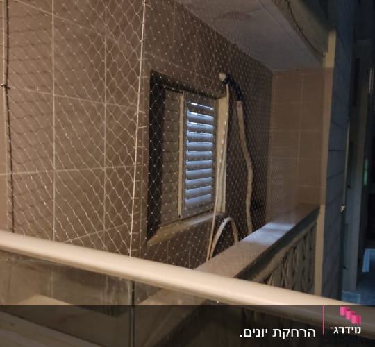 רשת הגנה מותקנת על חלון למניעת כניסת יונים